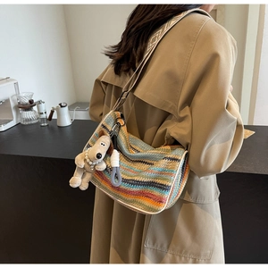 Detail of colorful rainbow woven bag with patterned shoulder strap and plush dog pendant