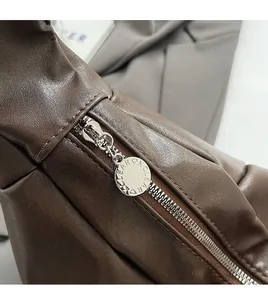 Close-up of soft brown leather handbag featuring a smooth silver circular metal zipper