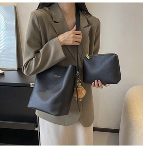 Detail of black lychee grain bucket bag and matching pouch with elegant plush charm
