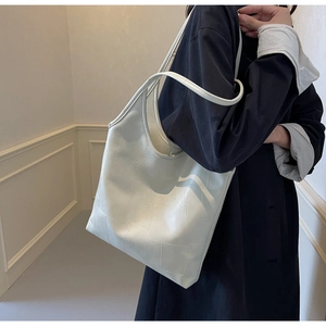 Detail view of beige tote bag featuring geometric stitching and pebbled leather texture