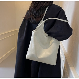Model wearing a minimalist cream leather tote bag with unique stitched texture detail