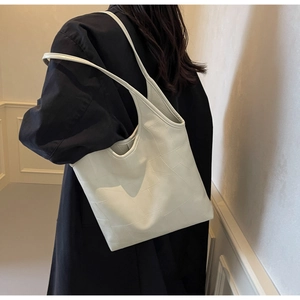 Close-up of cream leather tote bag featuring geometric stitching and long shoulder straps