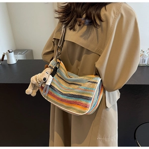 Rainbow woven hobo bag detail with plush dog charm and striped multi-color texture
