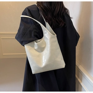 Detail of off-white tote bag with geometric texture shown on model's shoulder