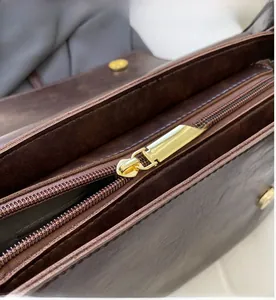 Macro shot of smooth gold-tone metal zipper and textured dark brown leather material