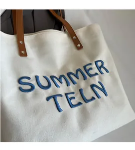Gros plan sur la broderie bleue SUMMER TELN sur tote bag en toile avec poignées en cuir