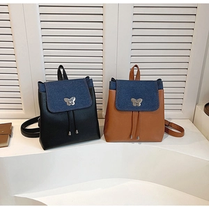 Detail of backpack flap featuring butterfly metal buckle and denim leather patchwork