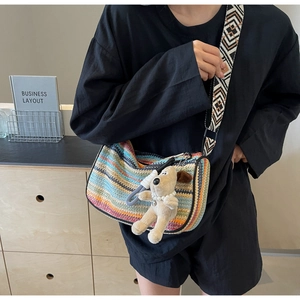 Detailed texture of rainbow woven crossbody bag with pattern strap and puppy pendant