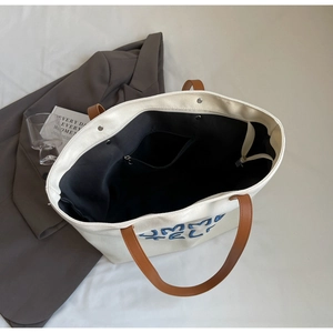 Vue de dessus du grand sac cabas en toile avec anses en cuir brun et fermeture éclair