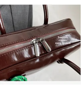 Détail des doubles fermetures éclair argentées sur un sac bowling marron foncé