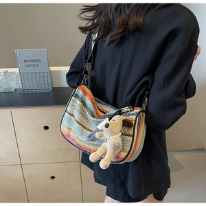 Detailed shot of rainbow woven crossbody bag with cute plush puppy charm and wide strap