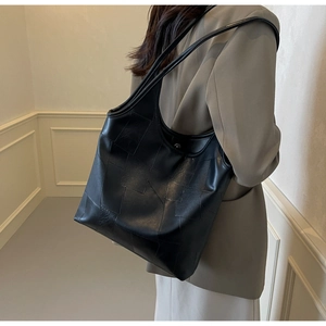 Detail of the black geometric patchwork tote bag shown from a side view on a model