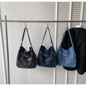 Detailansicht von Denim-Taschen in Anthrazit, Dunkelblau und Hellblau am Kleiderbügel