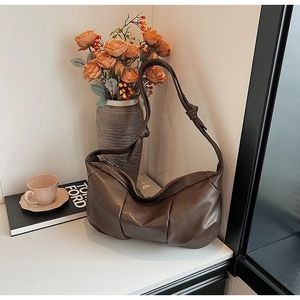 Detail of dark brown hobo bag with knotted shoulder strap and sleek metal zipper closure
