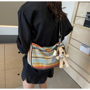 Detail of colorful woven crossbody bag with cute puppy plush charm on a model