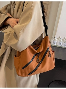 Brown nylon tote crossbody bag with black zippers and adjustable wide strap on a model