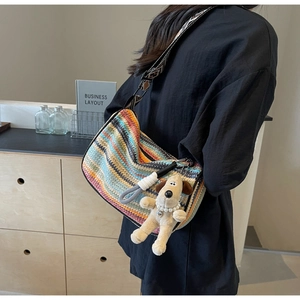 Detail of colorful rainbow woven bag with wide patterned strap and plush dog charm