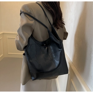 Detail of black geometric patchwork tote bag with matte leather and fine stitching