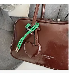 Détail du sac bowling en cuir marron foncé avec charm cœur et corde tressée décorative