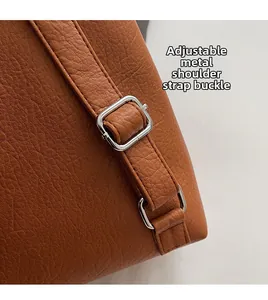 Detail of adjustable silver buckle on brown lychee pattern leather backpack strap