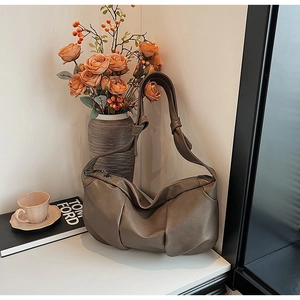 Detailed view of dark brown pleated soft leather crescent bag with stylish wide shoulder strap