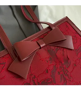 Close-up of wine red jacquard bridal tote bag with elegant leather bow and floral texture