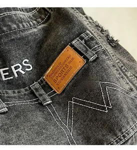 Detaillierte Nahaufnahme der schwarzen Denim-Taille mit Kontrastnähten und Lederetikett