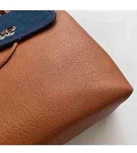 Macro shot of brown lychee grain leather and blue denim patchwork with silver buckle