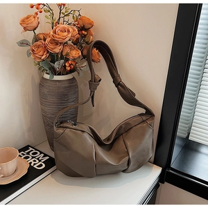 Detail of soft dark brown pleated faux leather shoulder bag on white marble surface