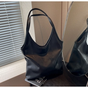 Detailed view of black leather tote bag featuring geometric stitching and long handles