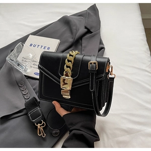 Detail of black crossbody bag featuring contrast stitching and bold gold chain decoration