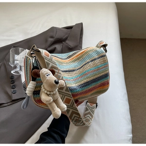 Detail of colorful striped straw bag featuring a cute plush dog pendant and wide strap