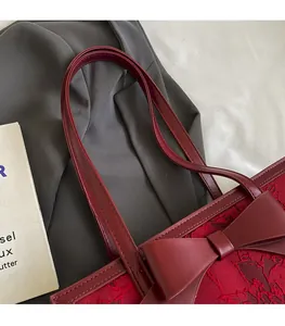 Detail of red jacquard bridal tote featuring a large leather bow and slim shoulder strap