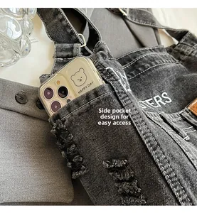 Detailansicht der Denim-Umhängetasche mit Seitentasche und abgenutzten Fransenrändern