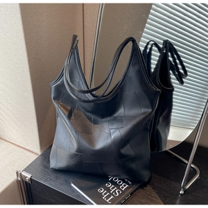 Detailed view of black textured leather hobo bag with irregular square pattern