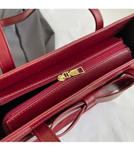 Macro detail of smooth golden zipper and red leather texture on luxury bridal tote bag