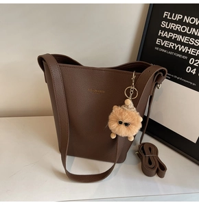 Detail of dark brown litchi pattern leather bucket bag with a cute teddy bear charm