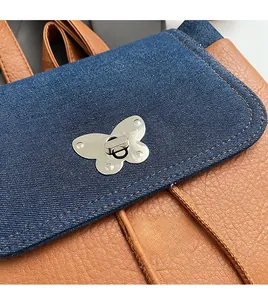 Close-up of luxury butterfly metal lock on brown leather and denim patchwork backpack