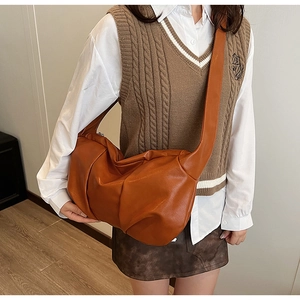 Detail view of caramel pleated leather shoulder bag with soft texture and slouchy design