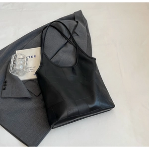 Detail of black leather tote bag with geometric square pattern and slim shoulder straps