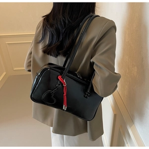 Détail du sac bowling en cuir verni noir brillant avec corde rouge et breloque cœur