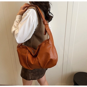 Detail of soft pleated brown faux leather handbag with wide knotted shoulder strap