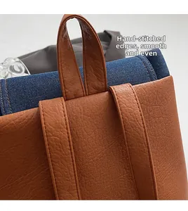 Detail of reinforced brown leather handle and blue denim stitching on the backpack