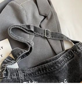 Detail des verstellbaren Denim-Schultergurts und der Metallschnalle an der schwarzen Tasche