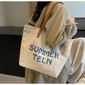 Détail du grand sac cabas en toile avec broderie bleue et anses en cuir marron