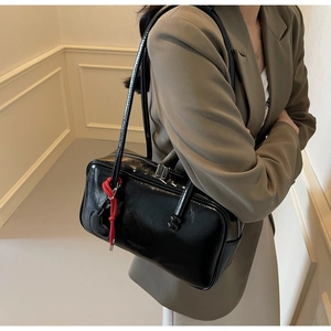 Détail d'un sac bowling vintage en cuir verni noir avec décoration en corde rouge