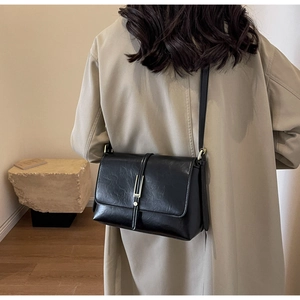 Detailed shot of a vintage black leather crossbody bag with a gold metal buckle detail