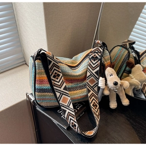 Macro detail of rainbow knit texture and geometric embroidered strap on a woven crossbody bag