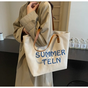 Détail du sac cabas en toile avec lettrage brodé bleu et fines lanières en cuir marron