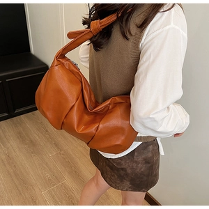 Detail of soft brown pleated hobo bag with knotted strap and smooth leather texture